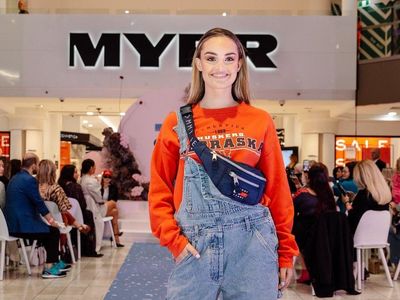 A model wearing an orange jumper with denim overalls