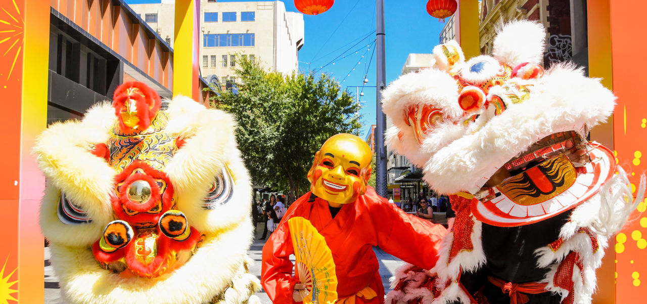 2 of the Lion Dancers in costume, with the God of Fortune in between them, celebrating Lunar New Year