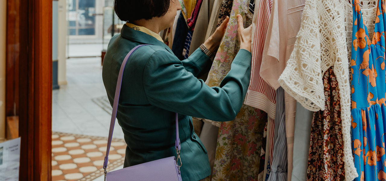 A well dressed lady looking through a rack of clothes