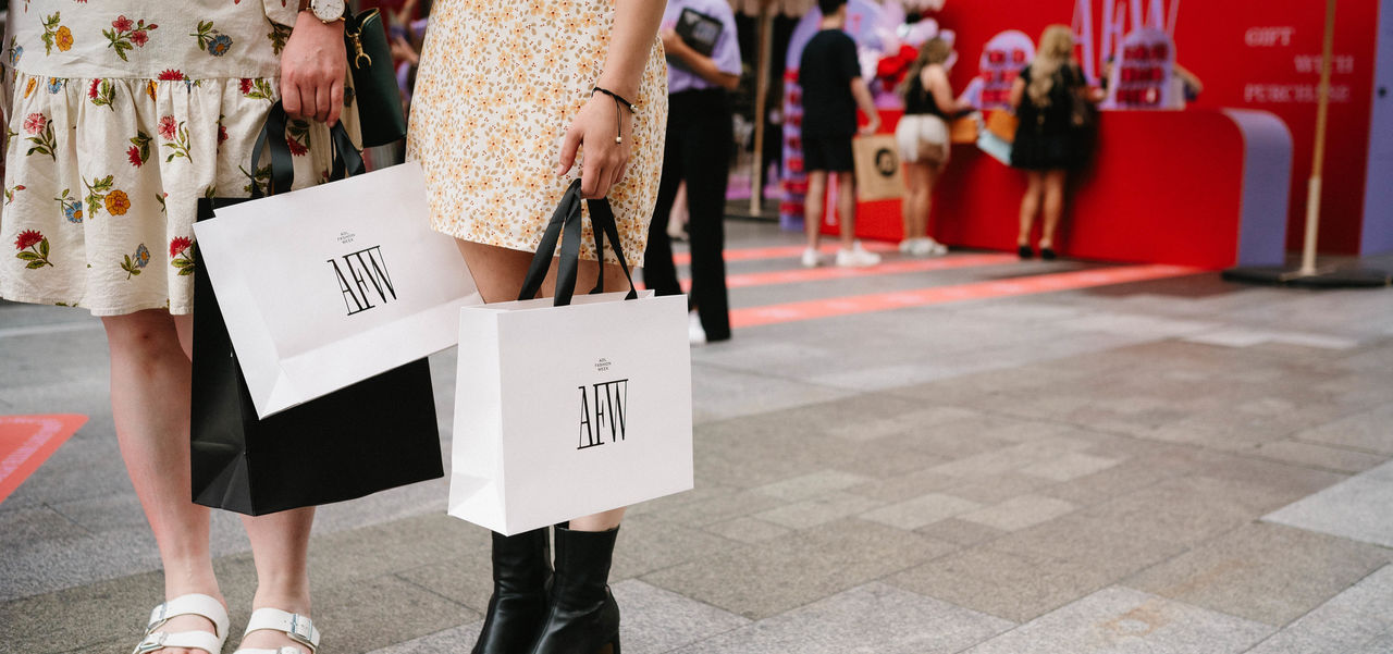Two girls holding ADL Fashion Week bags