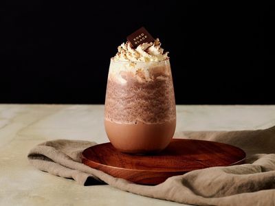A glass of iced chocolate with whipped cream on a wooden board