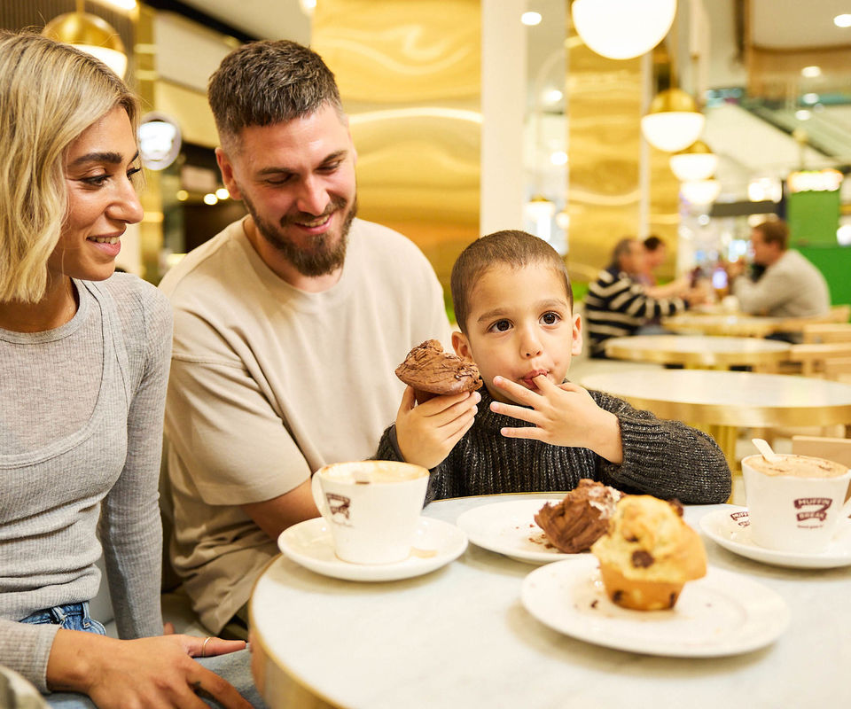 Family sitting in the food court eating muffins