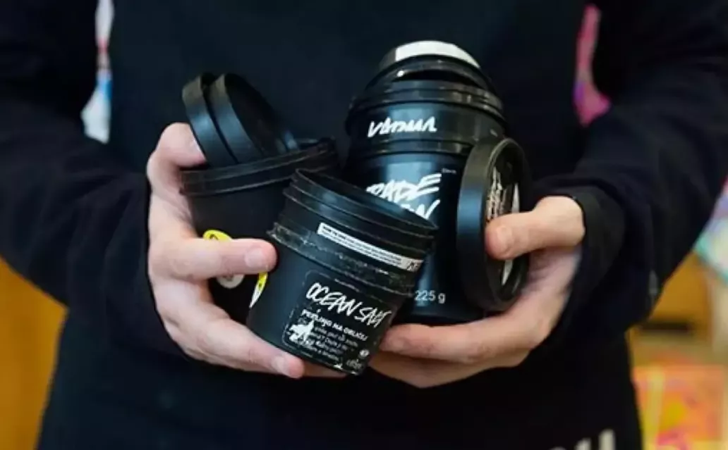 Person holding a stack of empty Lush packaging