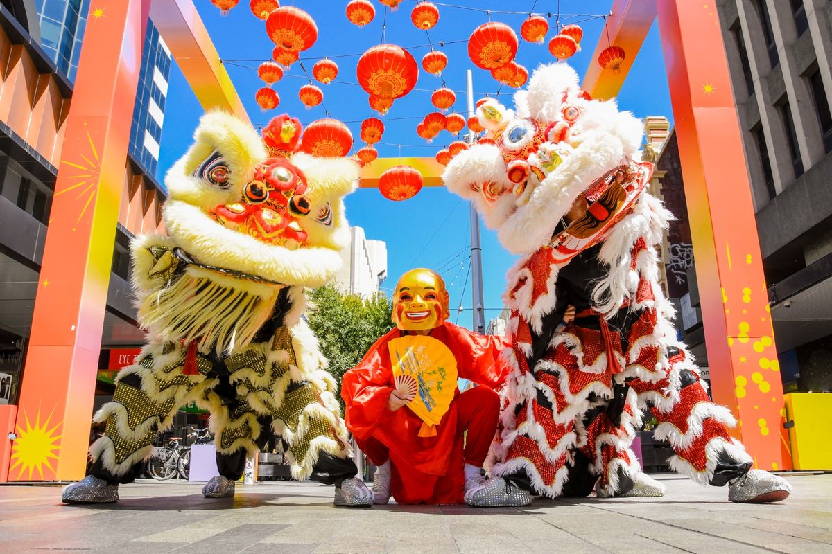 Lion dancers posing together in front of the red and yellow lanterns