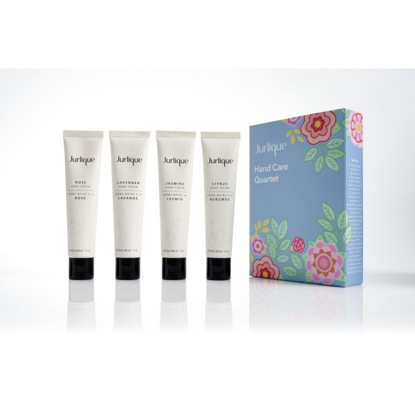 Four white tubes of hand cream next to a blue box