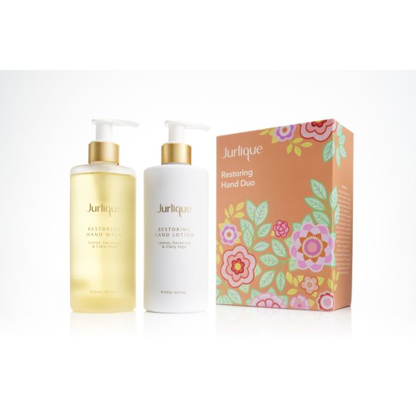 Two pump bottles of white cream and a gold liquid next to an orange gift box