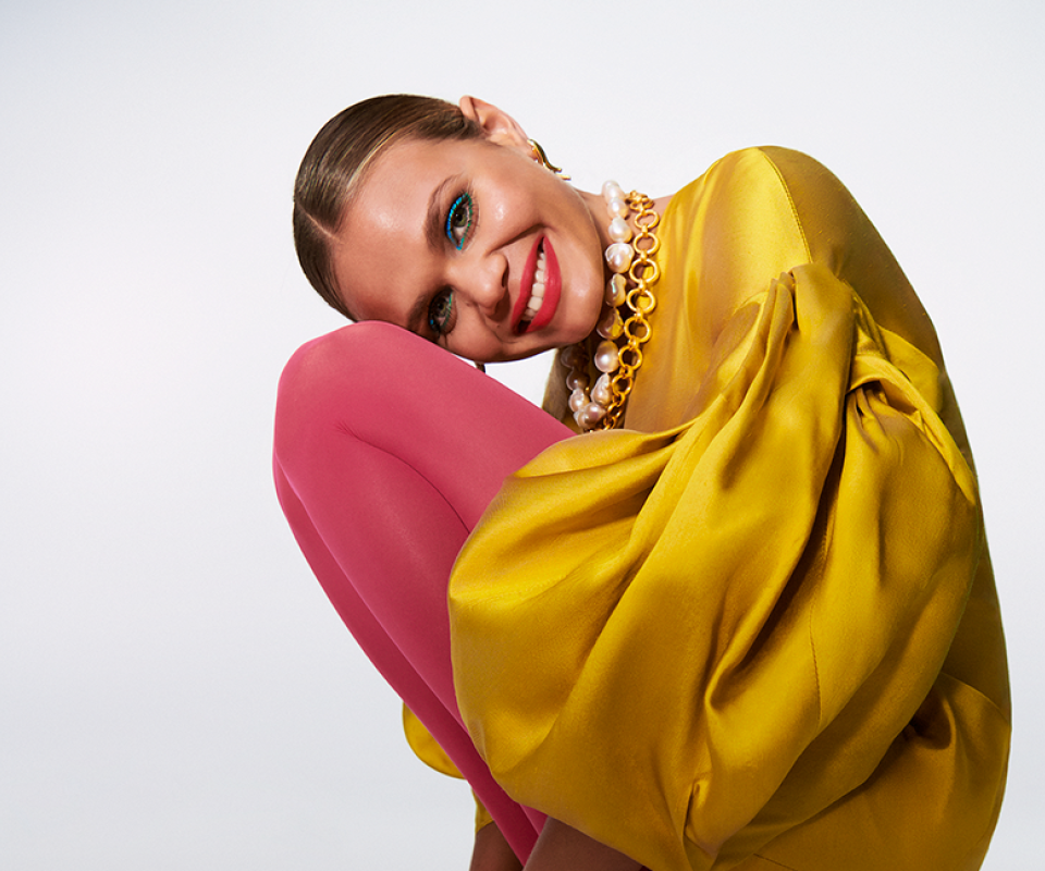 A woman wearing a yellow dress and crouching down