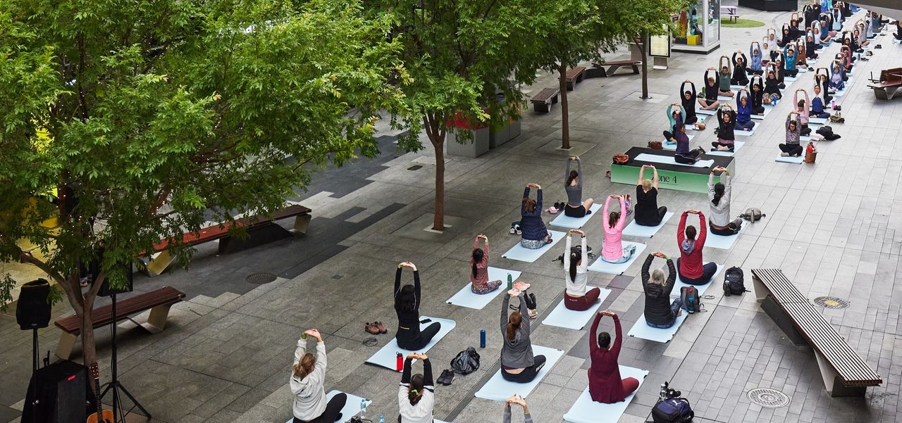 A large group of people doing yoga outside in Rundle Mall