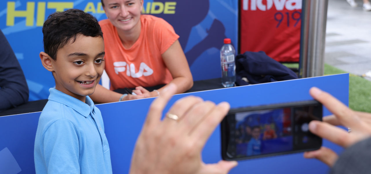 Child having a photo with one of the tennis players