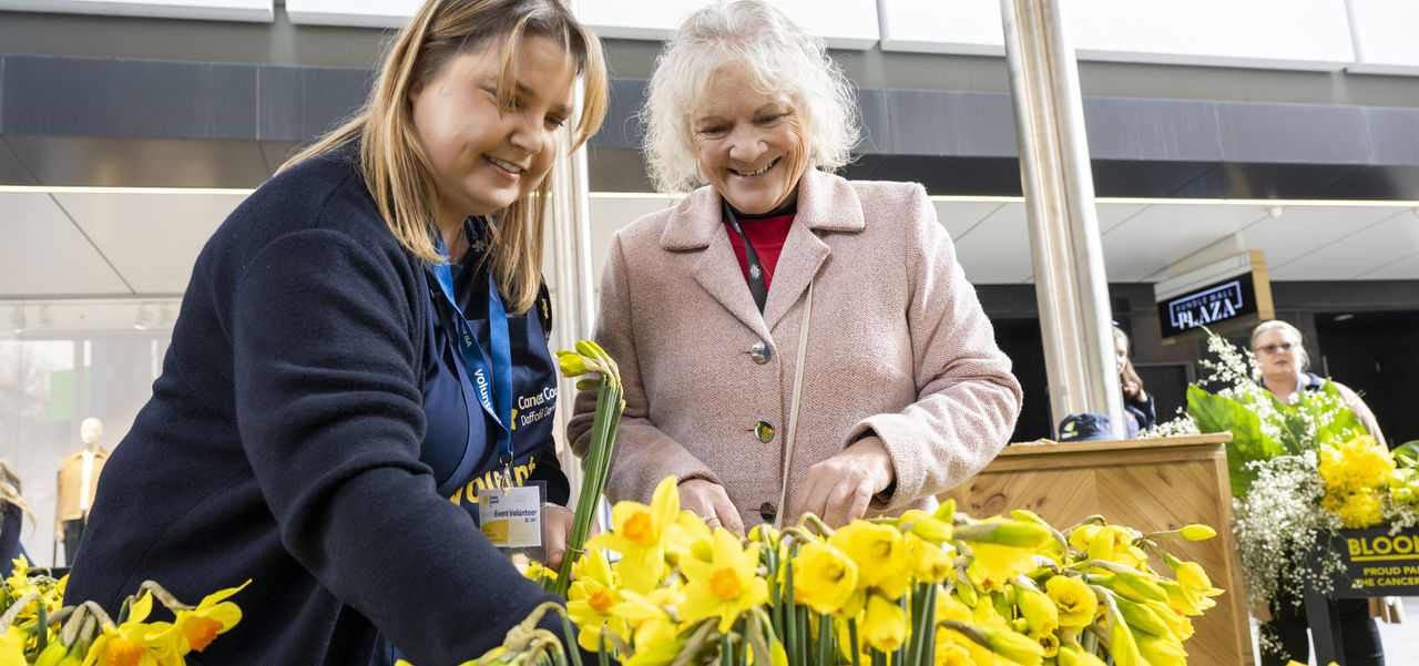 Lady and Cancer Council worker selecting daffodils