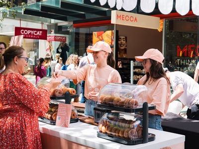Two girls in Go-To skincare peach t-shirts handing out free cinnamon donuts