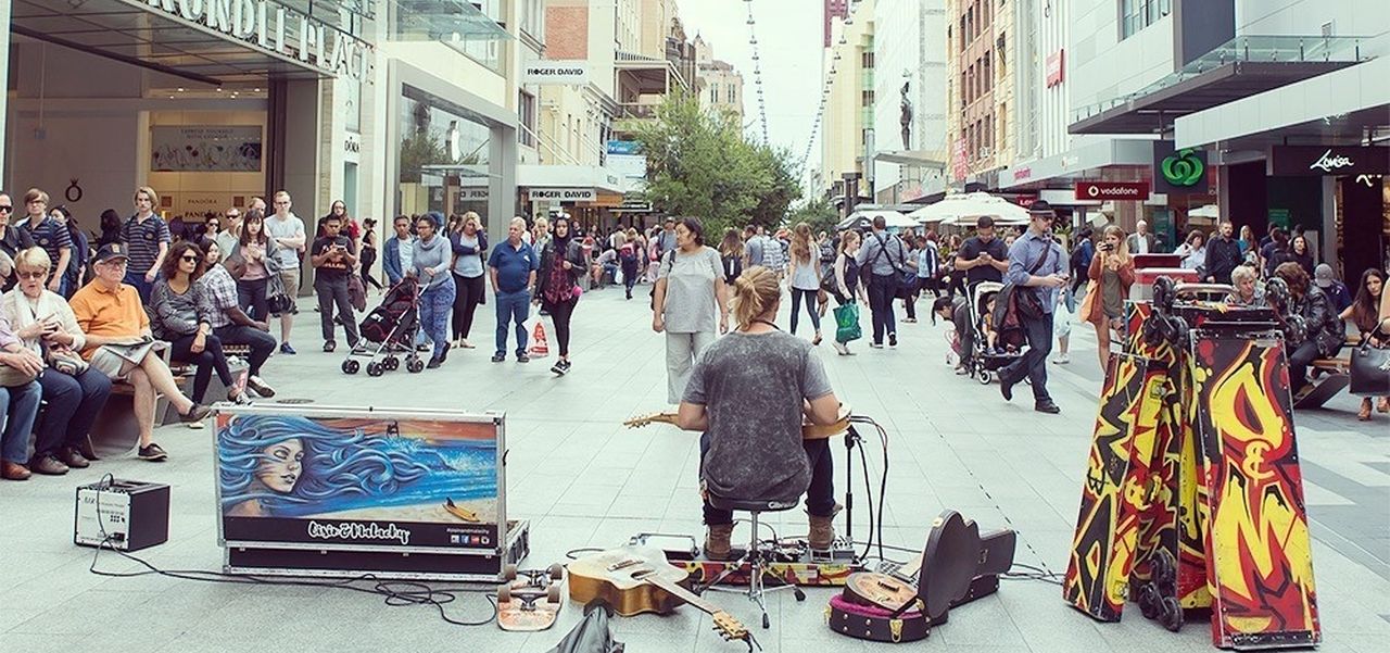 A man playing guitar in the centre of Rundle Mall with people watching