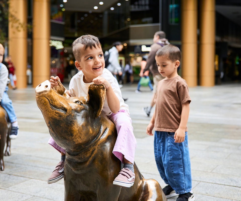 Two boys playing on the pigs in Rundle Mall