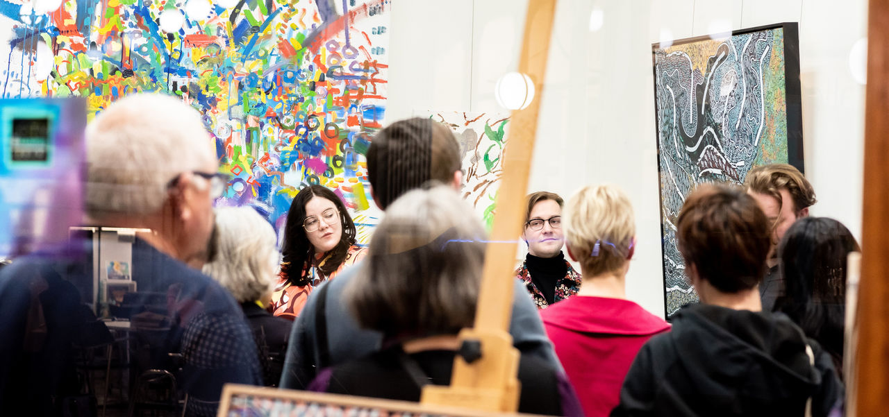 SALA event in a store with a crowd of people and lots of various paintings