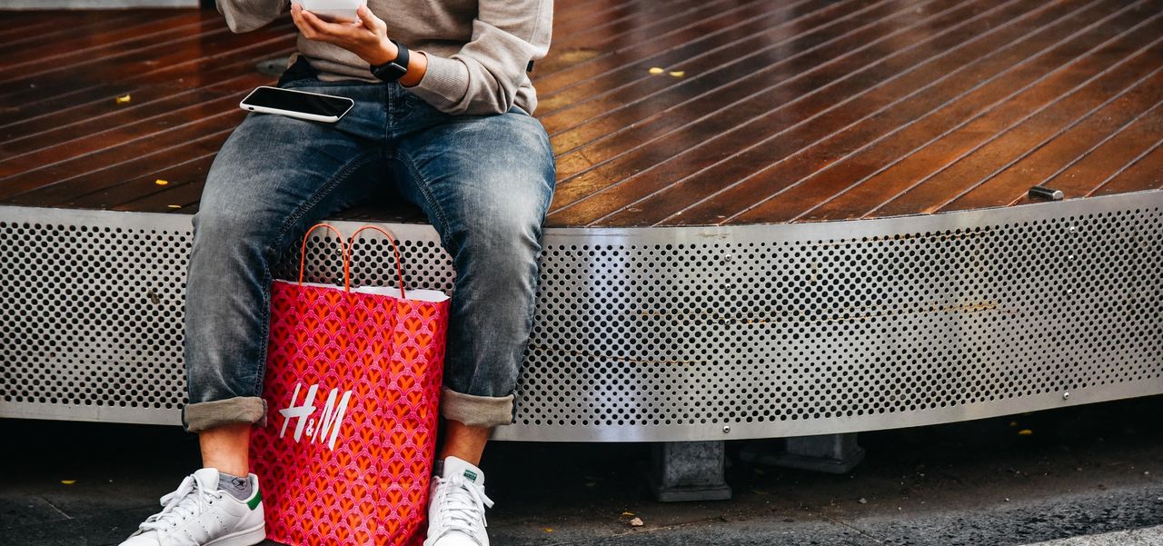 A man sitting on the pods in Rundle Mall with a red H&M bag at his feet.