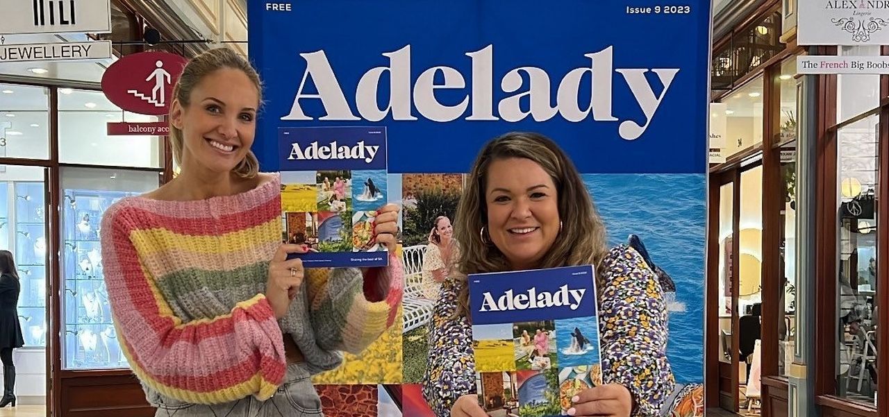 Lauren and Hayley from Adelady standing in front of the life size version of their new Adelady magazine.
