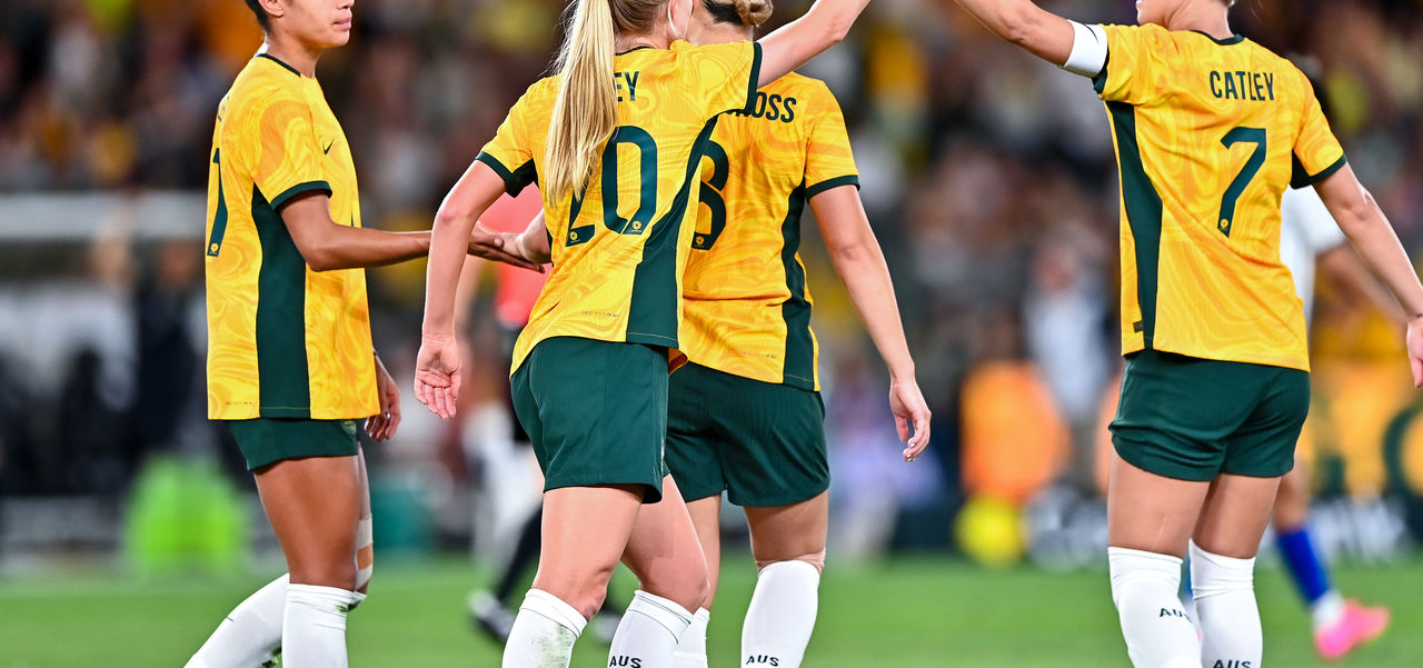 The Matilda's in a group on the soccer pitch high-fiving.