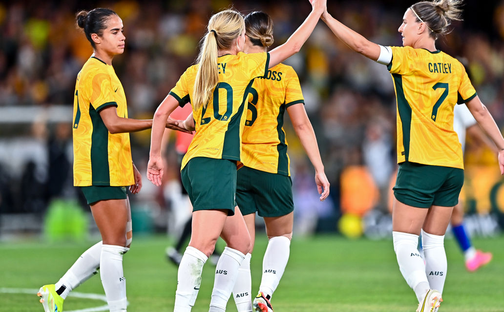 The Matilda's in a group on the soccer pitch high-fiving.
