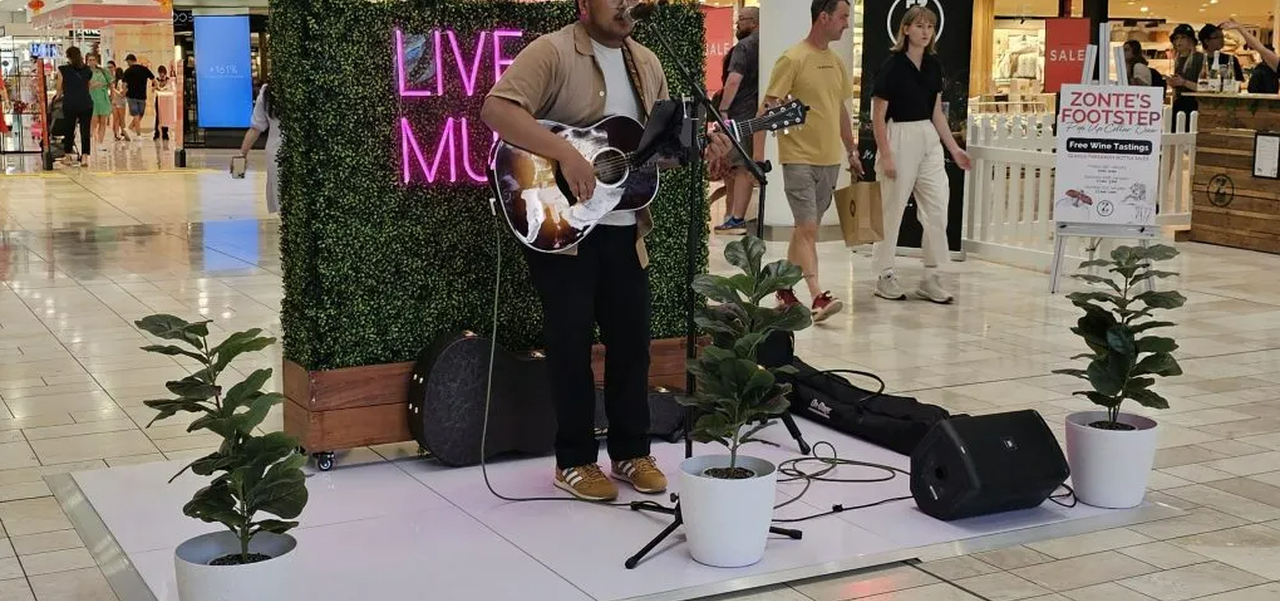 Man playing guitar on a mini stage in the Myer Centre
