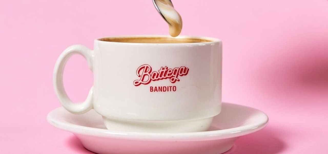 Bottega bandito coffee cup with a hand dipping a teaspoon into it